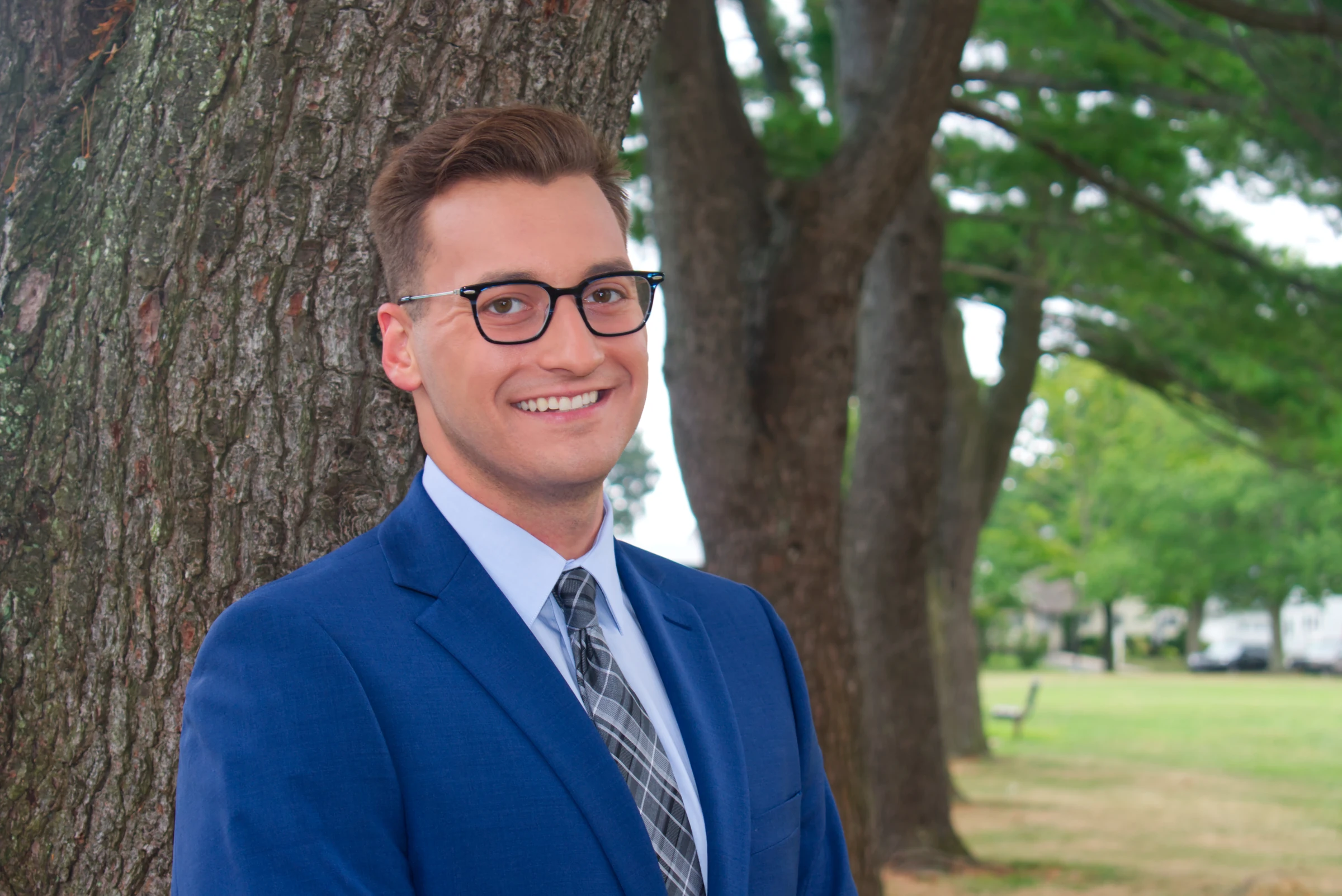 Corporate headshot of a man in a blue suit and tie, photographed outdoors in Boston